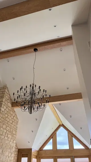 Black chandelier hanging beside a ceiling beam
