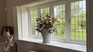 Vase of flowers on the sill of a leaded window