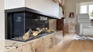 Glass-fronted fireplace set into a pale stone surround