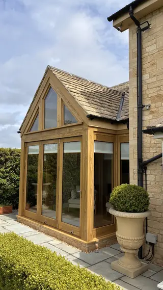 Accoya-clad steel-framed apex extension seen at an angle beside the stone house