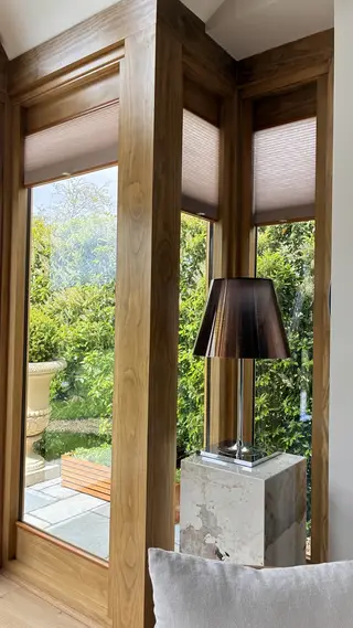 Corner glazing overlooking the garden beside a floor lamp