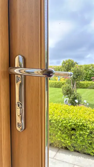 Polished handle on a glazed door with the garden beyond