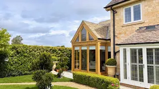Accoya-clad steel-framed glazed apex extension in a wide garden view