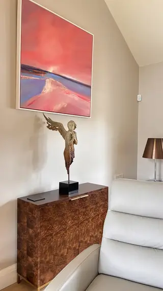 Bronze figure displayed on a console table beneath a painting