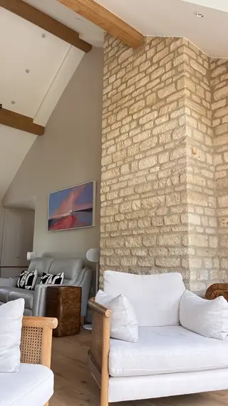Exposed stone wall beside a grey armchair and floor lamp