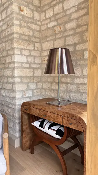 Wooden console table and lamp against an exposed stone wall