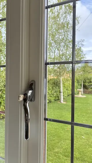 Black window latch with the garden visible beyond