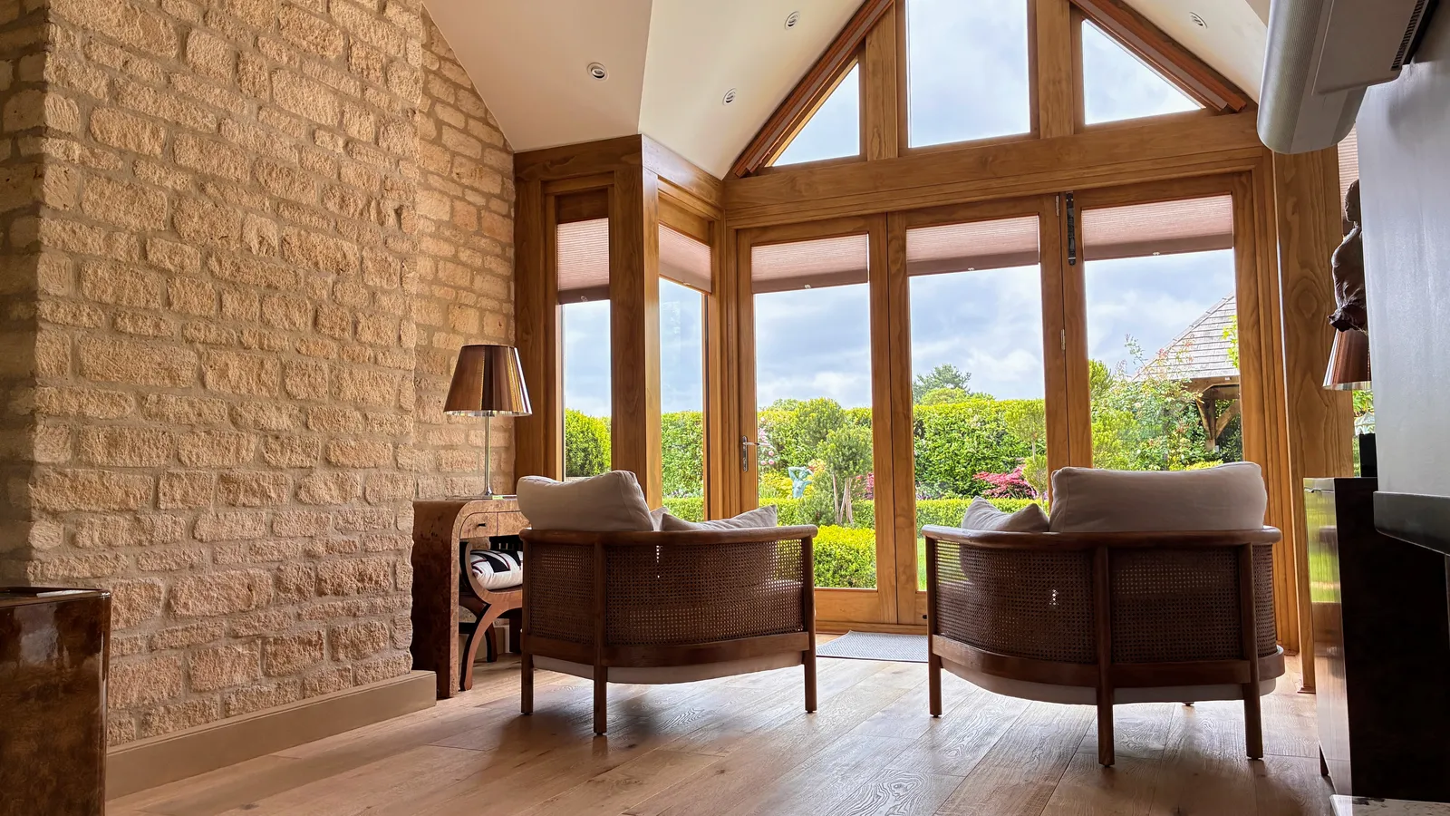 Charnwood House — interior vaulted living room with exposed Cotswold stone wall