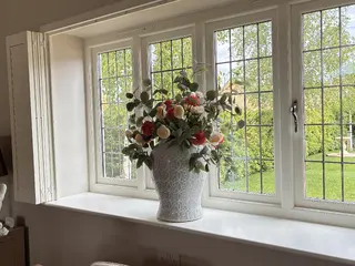 Vase of flowers on the sill of a leaded window
