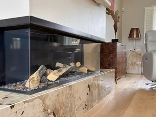 Glass-fronted fireplace set into a pale stone surround