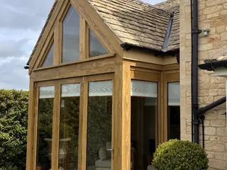 Oak-framed apex extension seen at an angle beside the stone house
