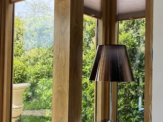 Oak corner glazing overlooking the garden beside a floor lamp