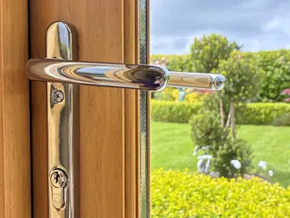 Polished handle on an oak door with the garden beyond