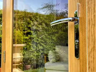 Close-up of a polished handle on an oak-framed glazed door