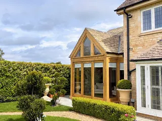 Oak-framed glazed apex extension in a wide garden view