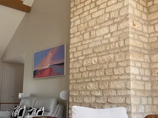 Exposed stone wall beside a grey armchair and floor lamp