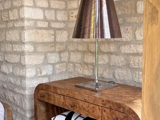 Wooden console table and lamp against an exposed stone wall