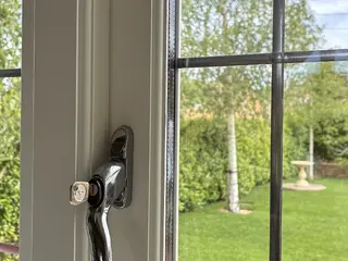 Black window latch with the garden visible beyond